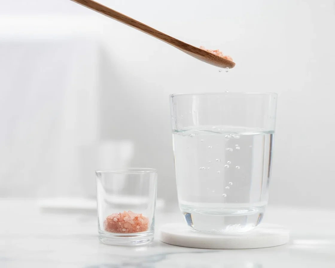 Woman holding a glass of pink salt water for weight loss